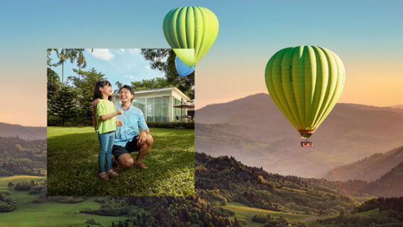 A man and his son fly a balloon, while hot air balloons fly over a mountain range.