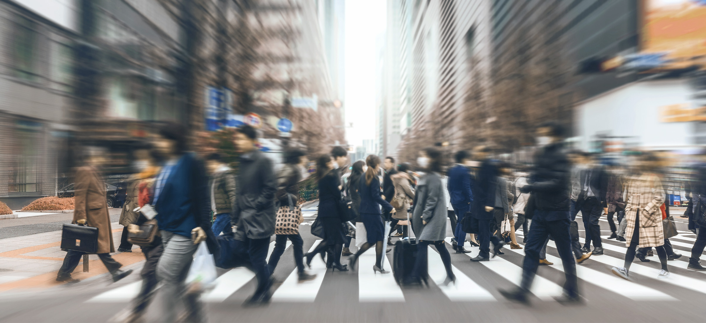 People walk across a zebra crossing in a busy urban street.