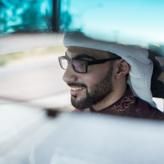 A man looks in the rear view mirror of his car.