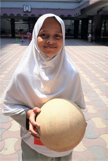 girl standing outside holding football